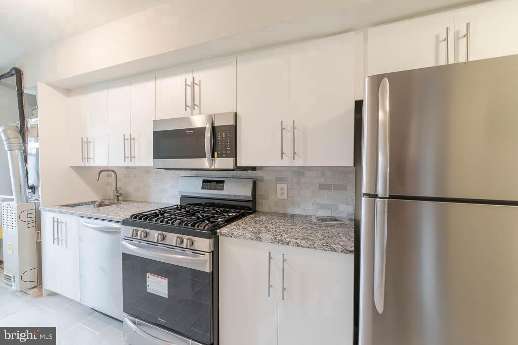 a kitchen with stainless steel appliances granite countertop a refrigerator stove and microwave