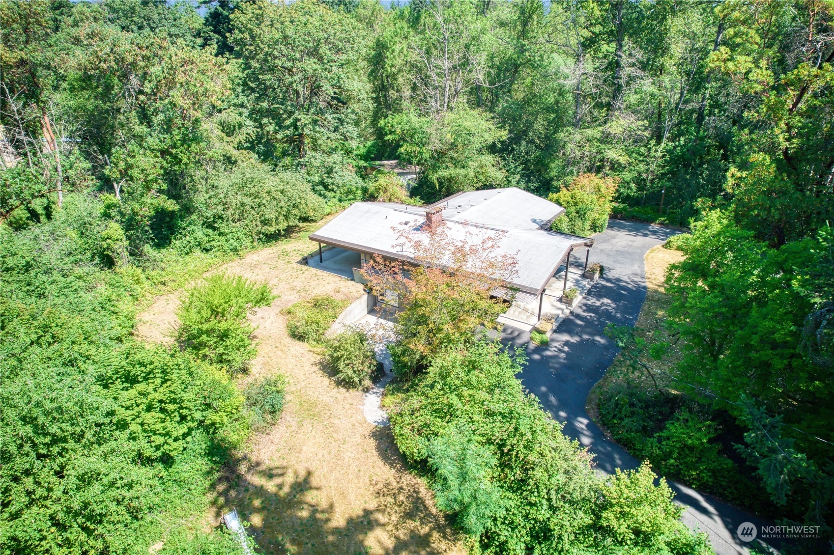 an aerial view of residential house with outdoor space and trees all around