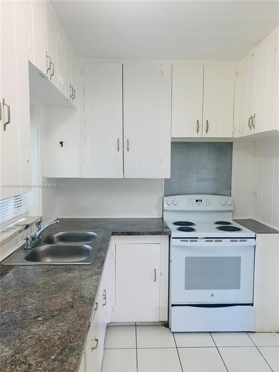 a kitchen with granite countertop white cabinets and white stove