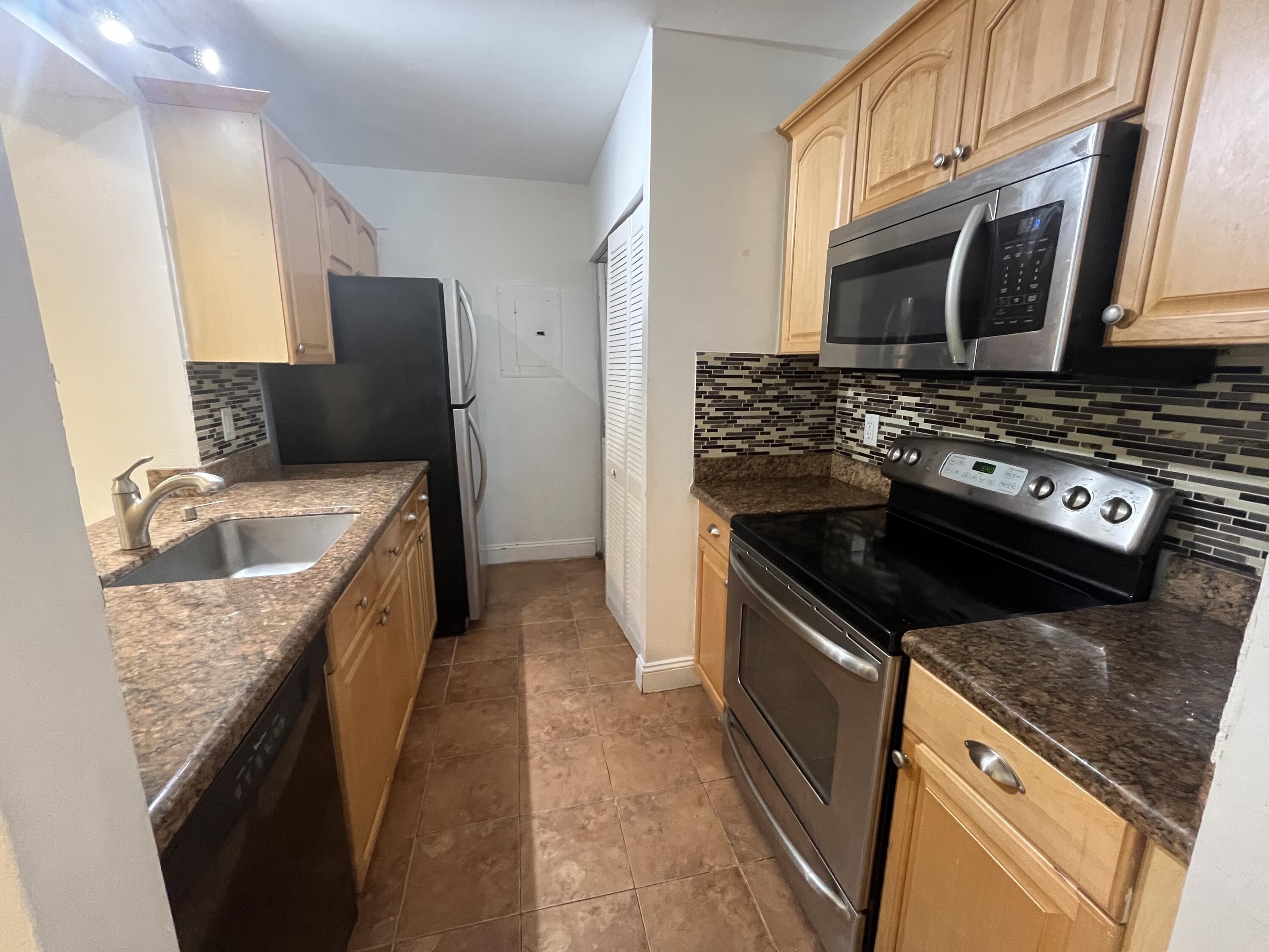 a kitchen with granite countertop a sink stove and refrigerator