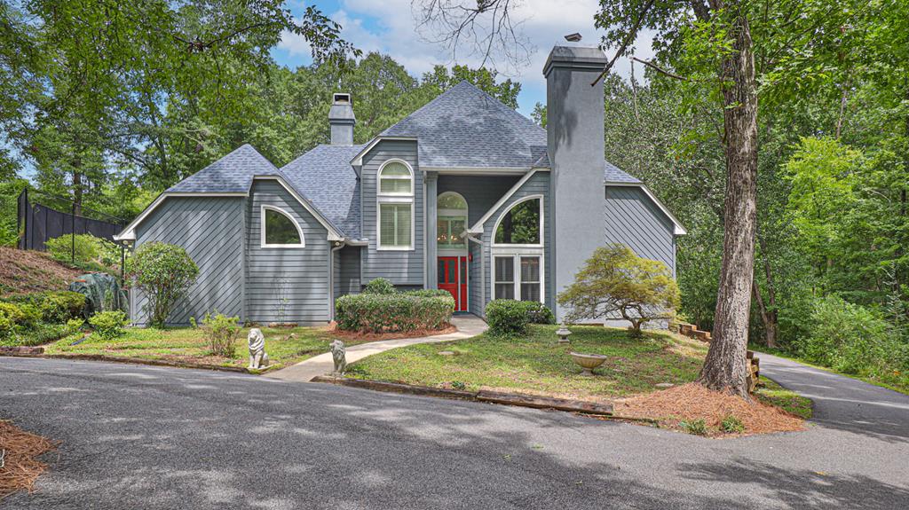 a view of a brick house with a yard plants and large tree