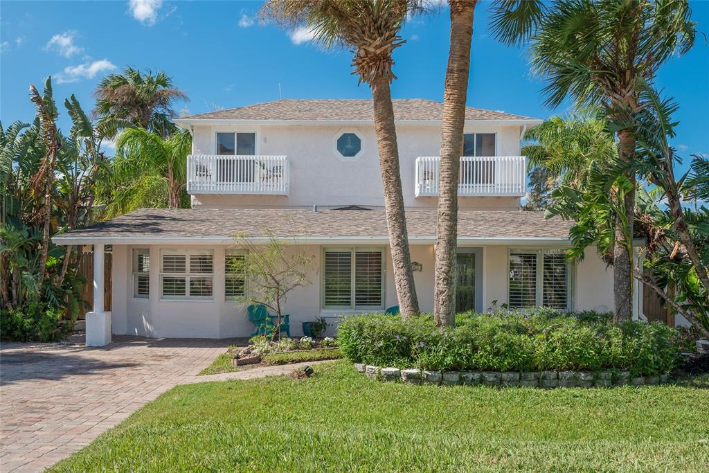 front view of a house with a yard and palm trees