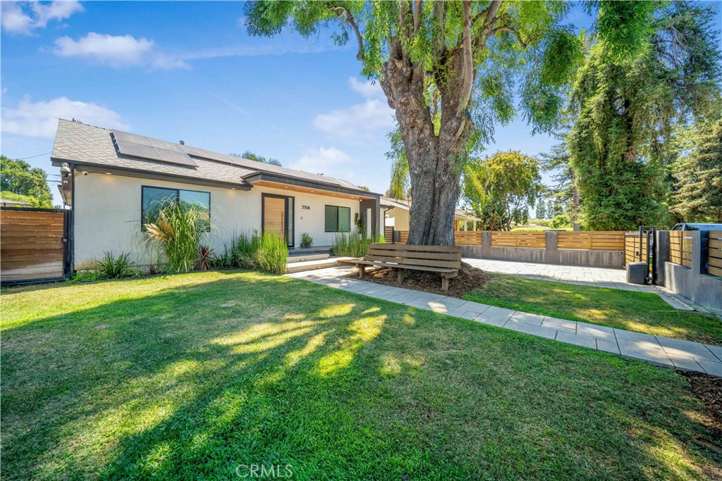 a backyard of a house with table and chairs plants and large tree