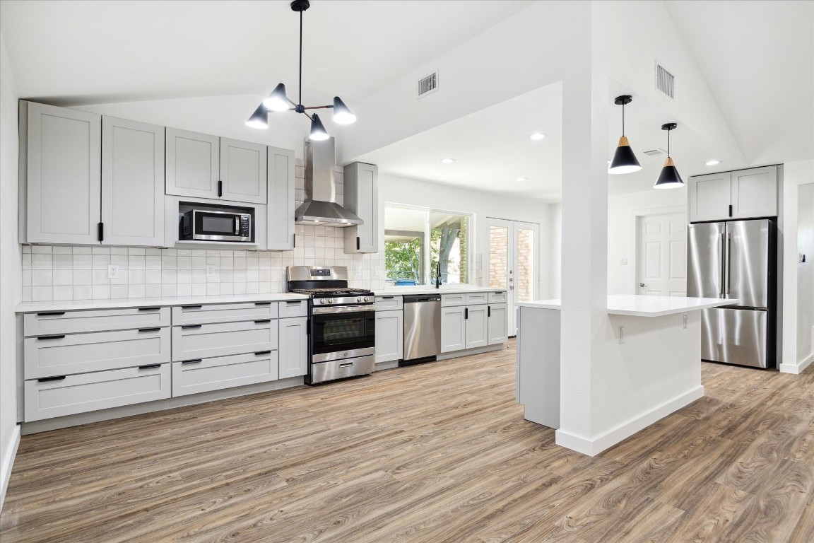 a kitchen with stainless steel appliances kitchen island granite countertop a stove a refrigerator and a wooden floor