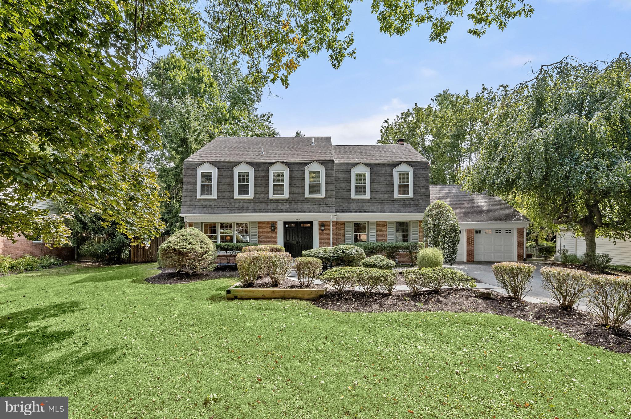 a front view of a house with a garden and trees