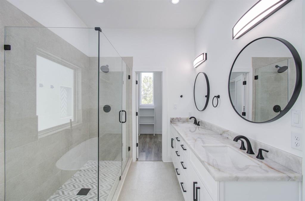 a bathroom with a double vanity sink mirror and shower