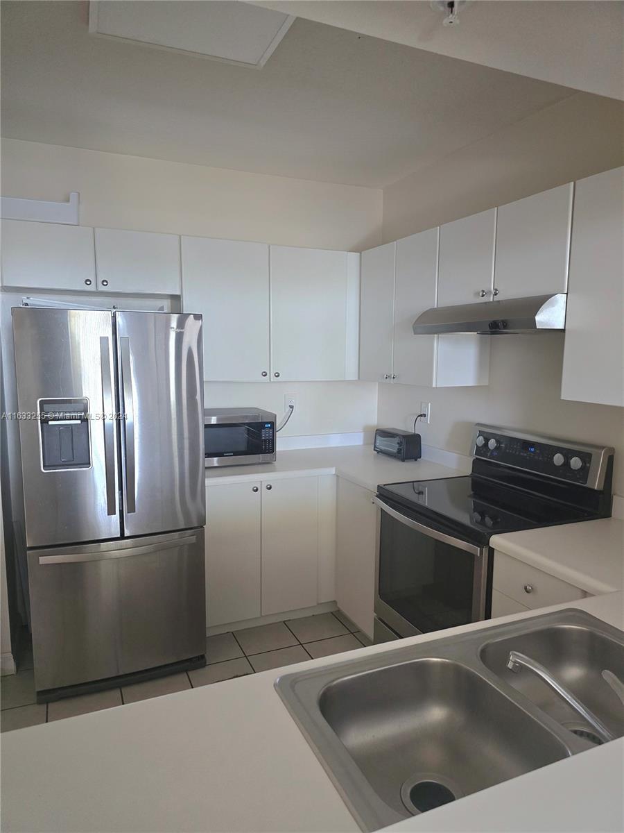 a kitchen with a refrigerator sink and cabinets