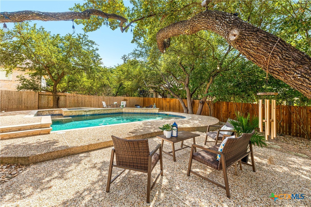 a patio with table and chairs and couches with wooden fence and plants