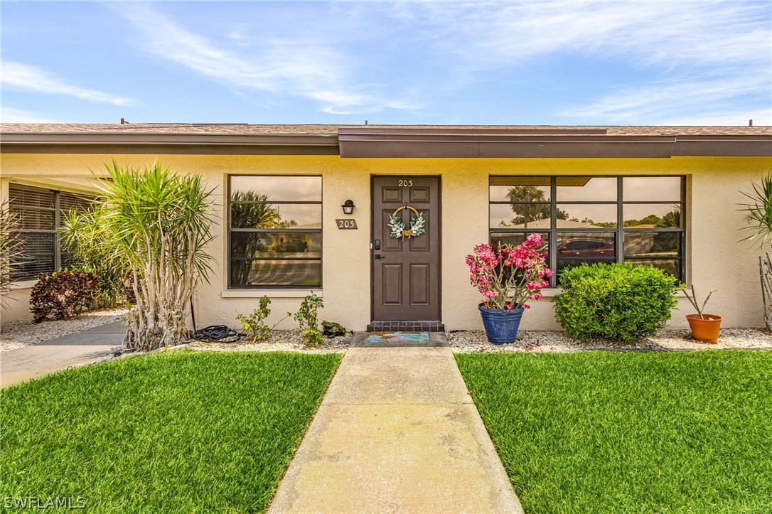 a front view of a house with a yard and potted plants