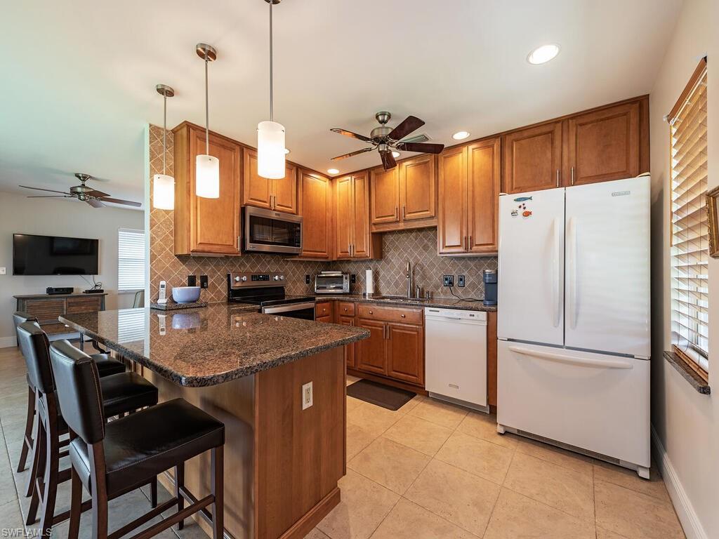 a kitchen with stainless steel appliances granite countertop a refrigerator a stove a sink and a microwave