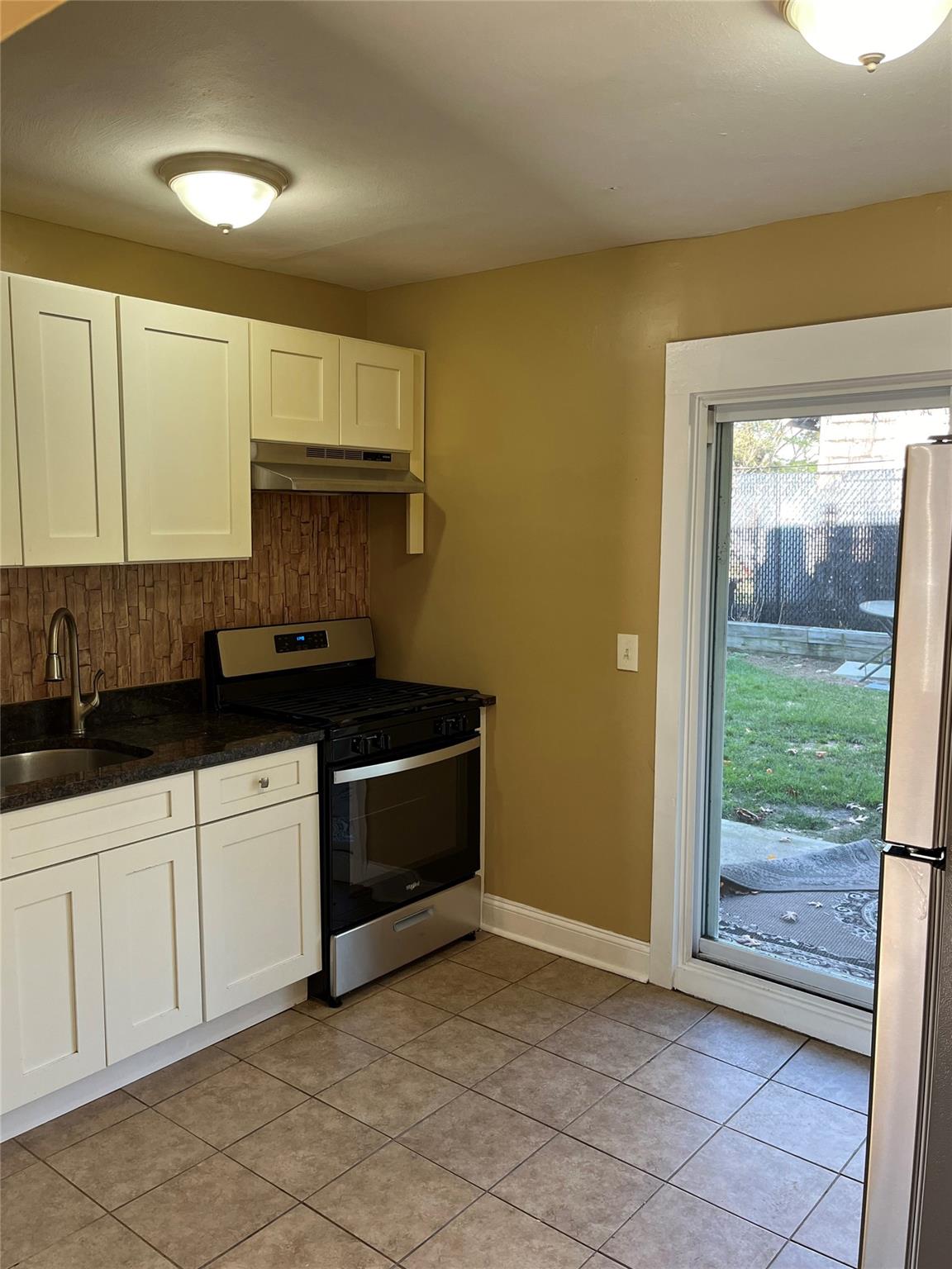 Kitchen featuring light tile patterned floors, white cabinetry, sink, and appliances with stainless steel finishes