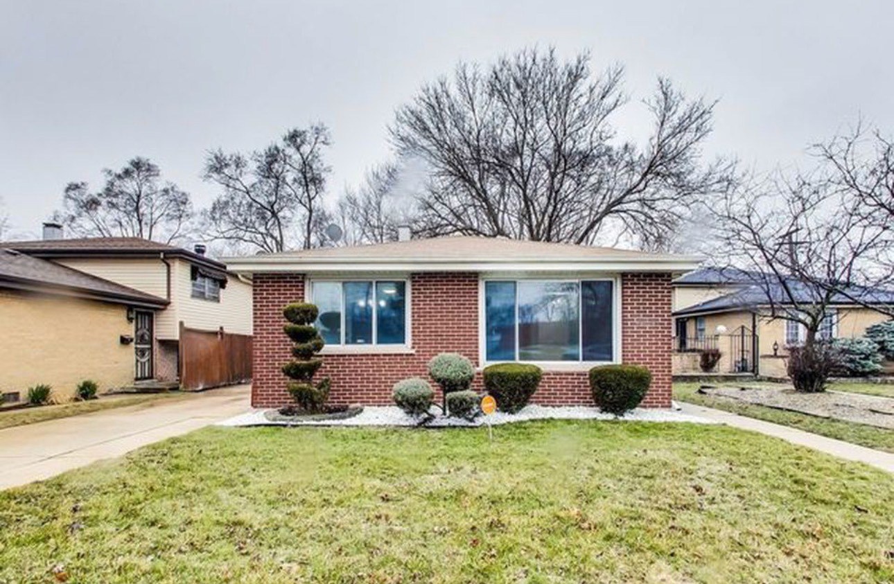 a front view of house with yard and trees around