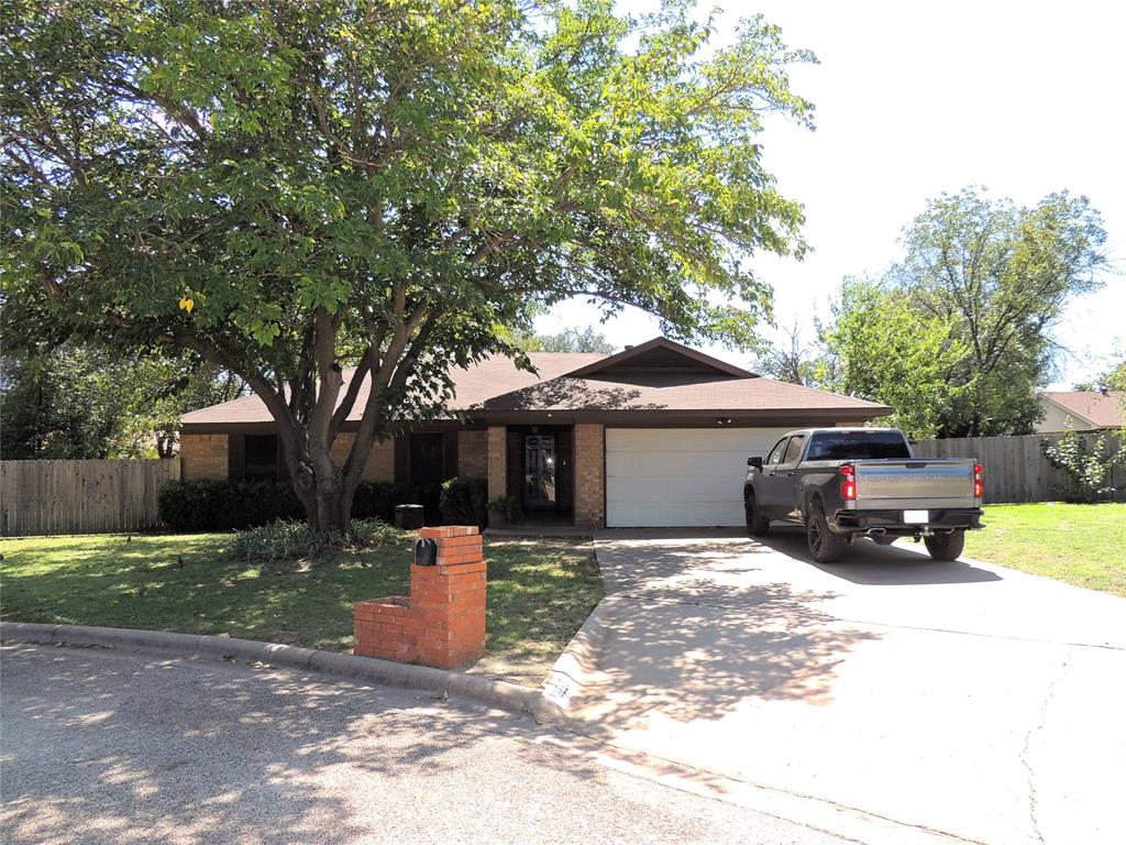 a view of a house with a yard and large tree