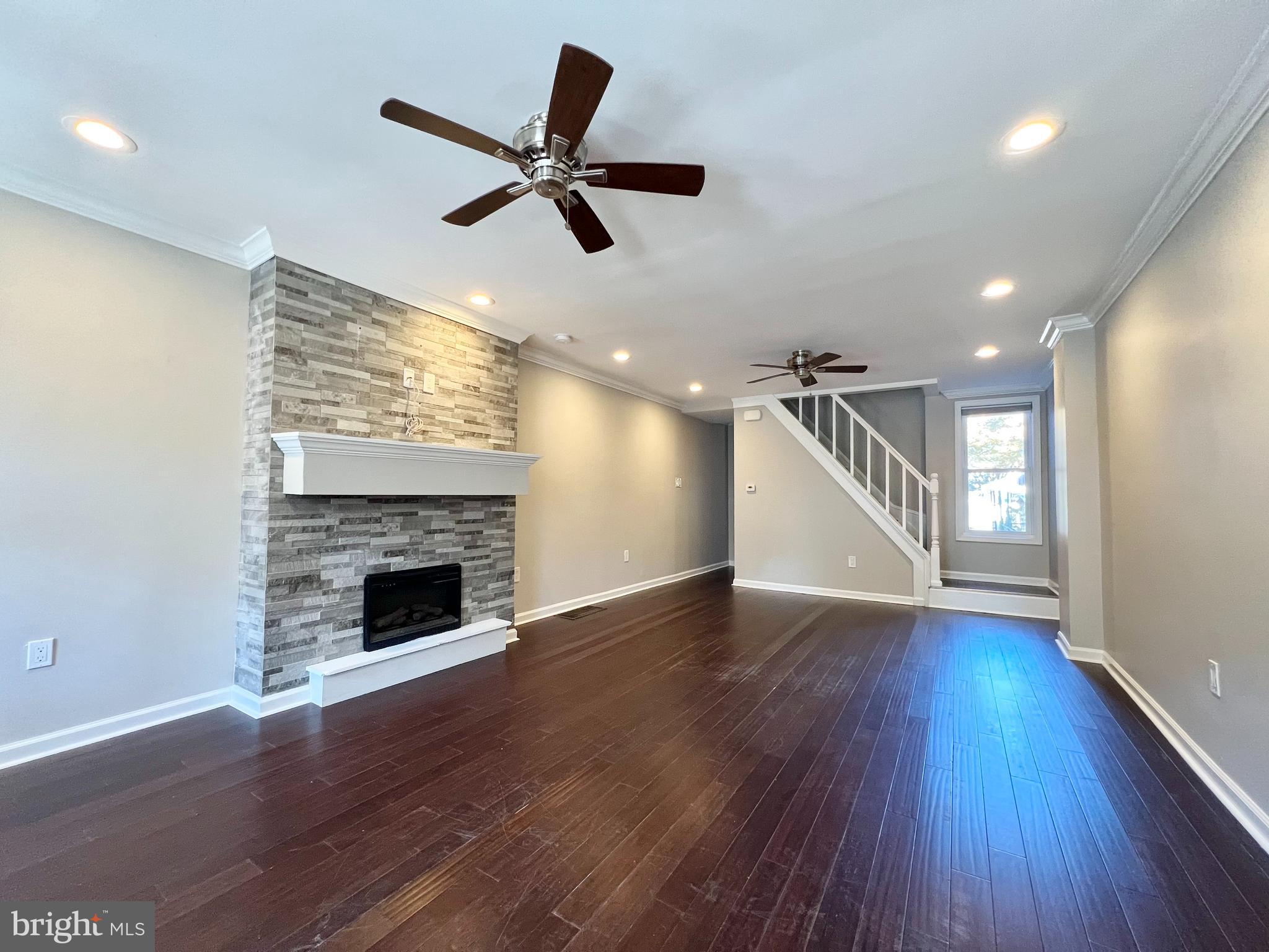 wooden floor in an empty room with a fireplace and a window