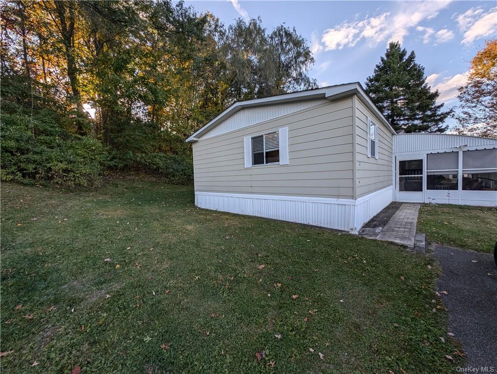 View of property exterior with a yard and a sunroom