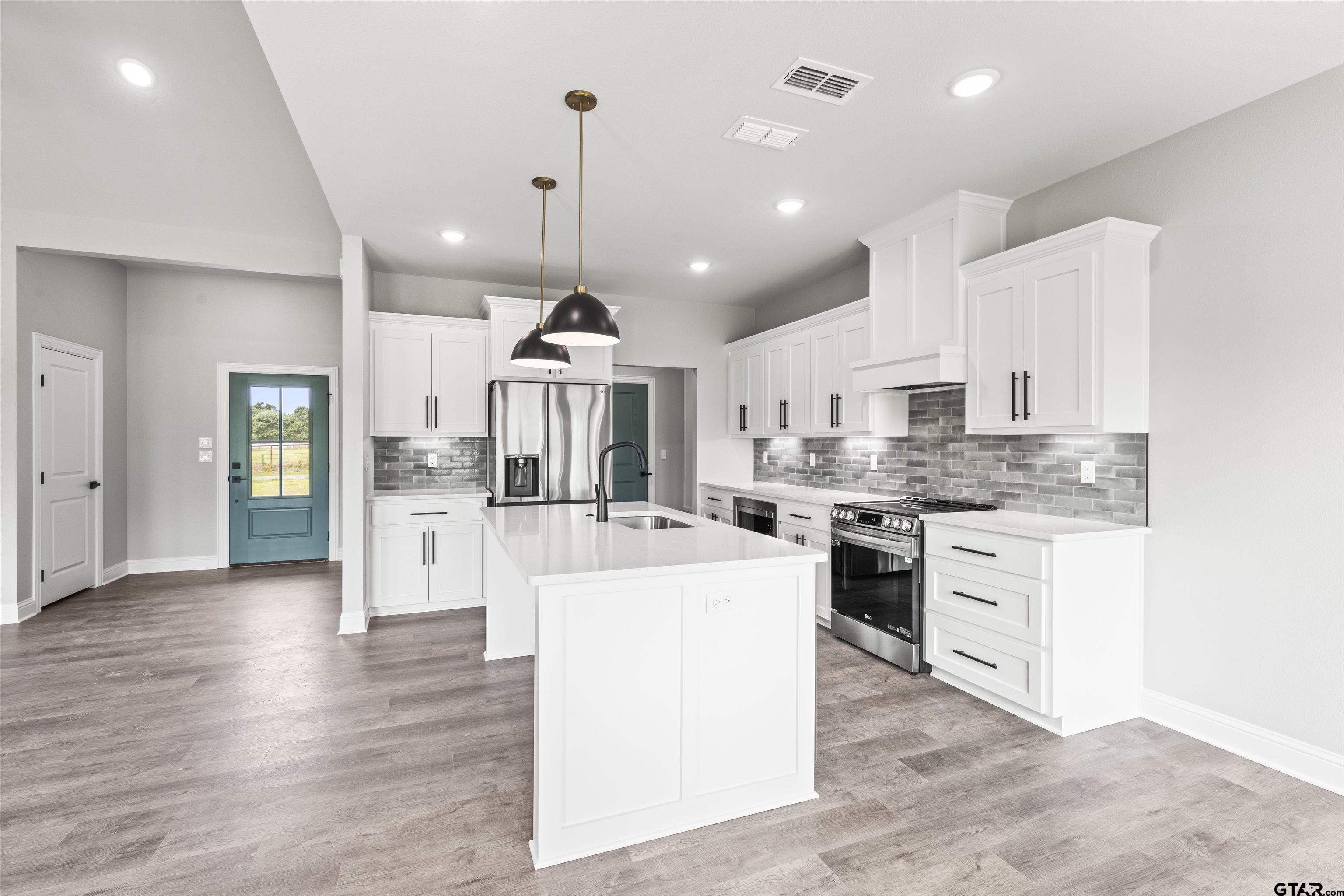 a large kitchen with kitchen island a sink a center island stainless steel appliances and cabinets