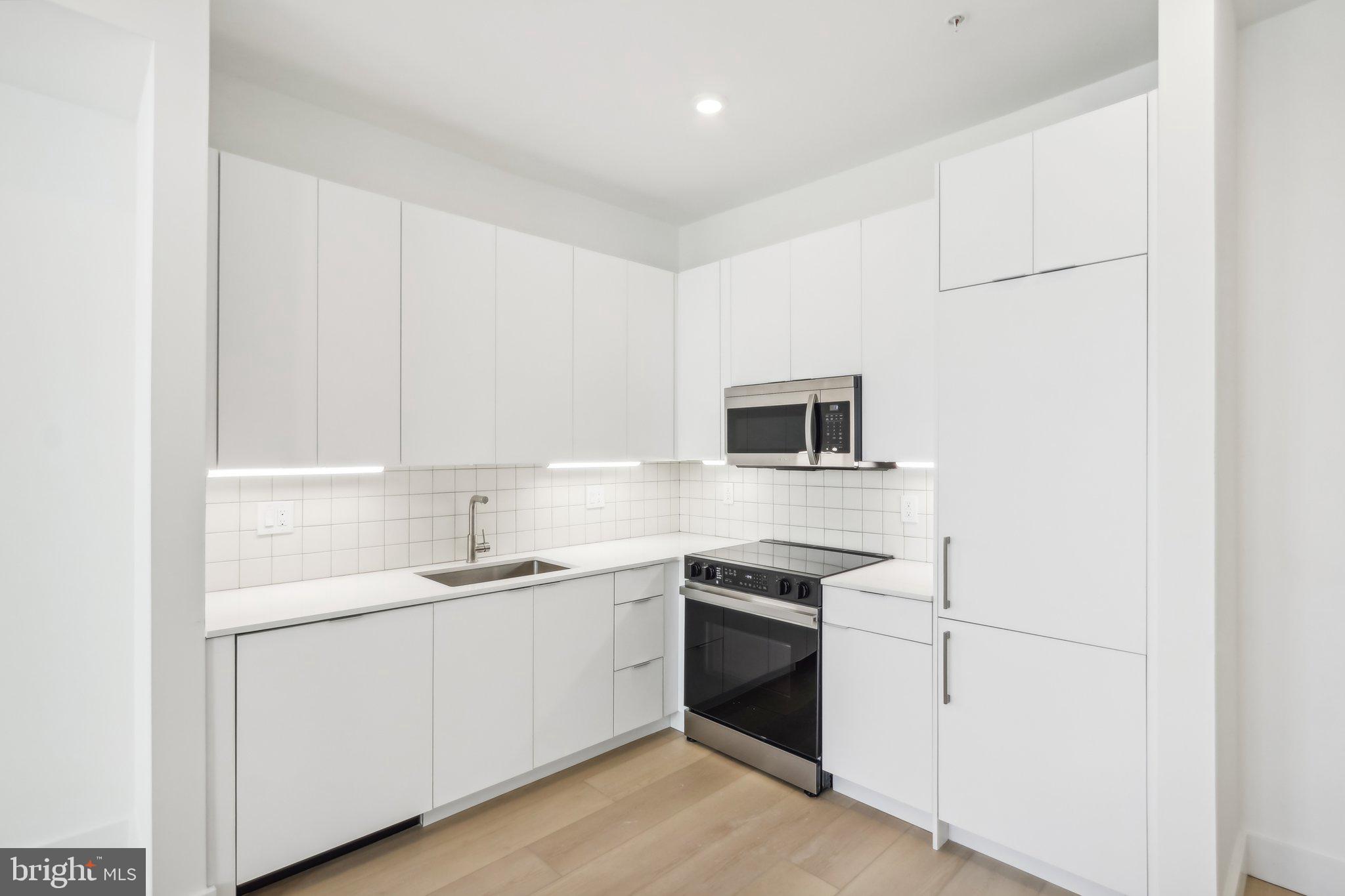 a kitchen with a sink white cabinets and white appliances