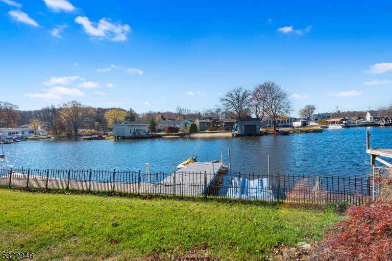 a view of a lake with lawn chairs and large trees