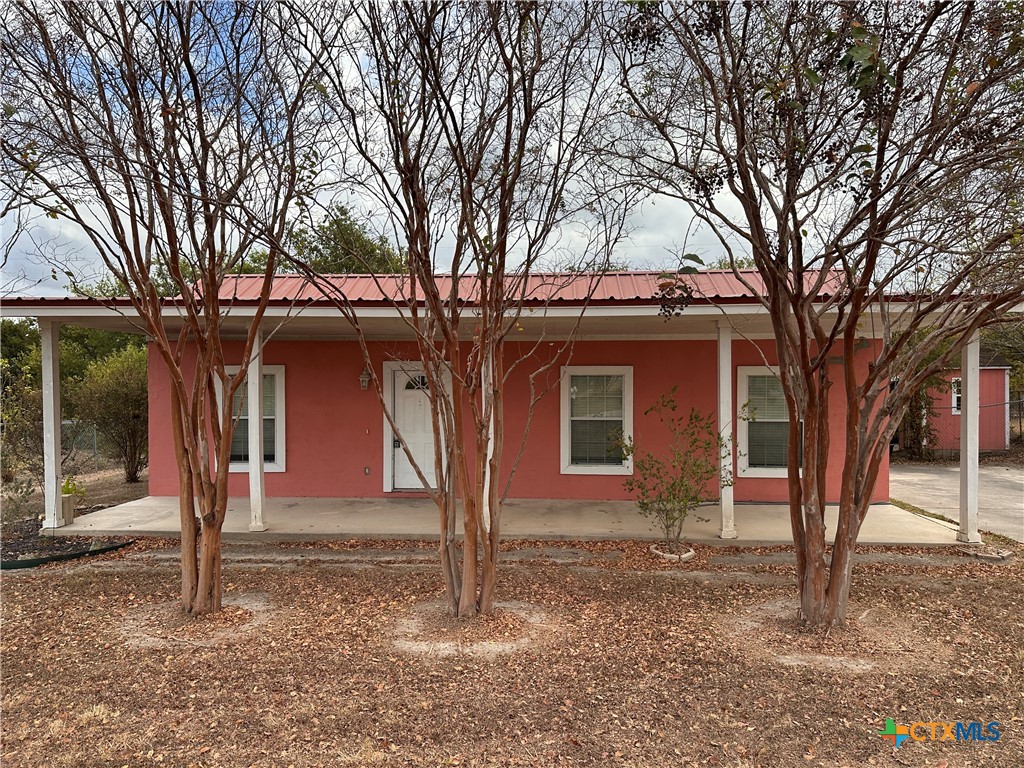 a front view of a house with a yard and large tree