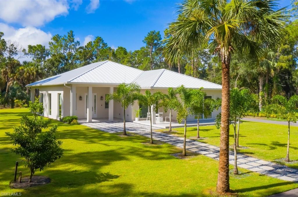 a backyard of a house with table and chairs under an umbrella