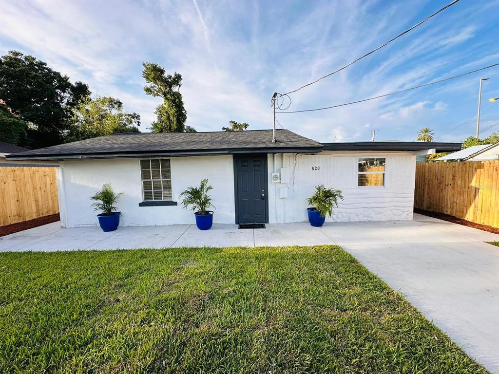 a front view of a house with a yard and potted plants