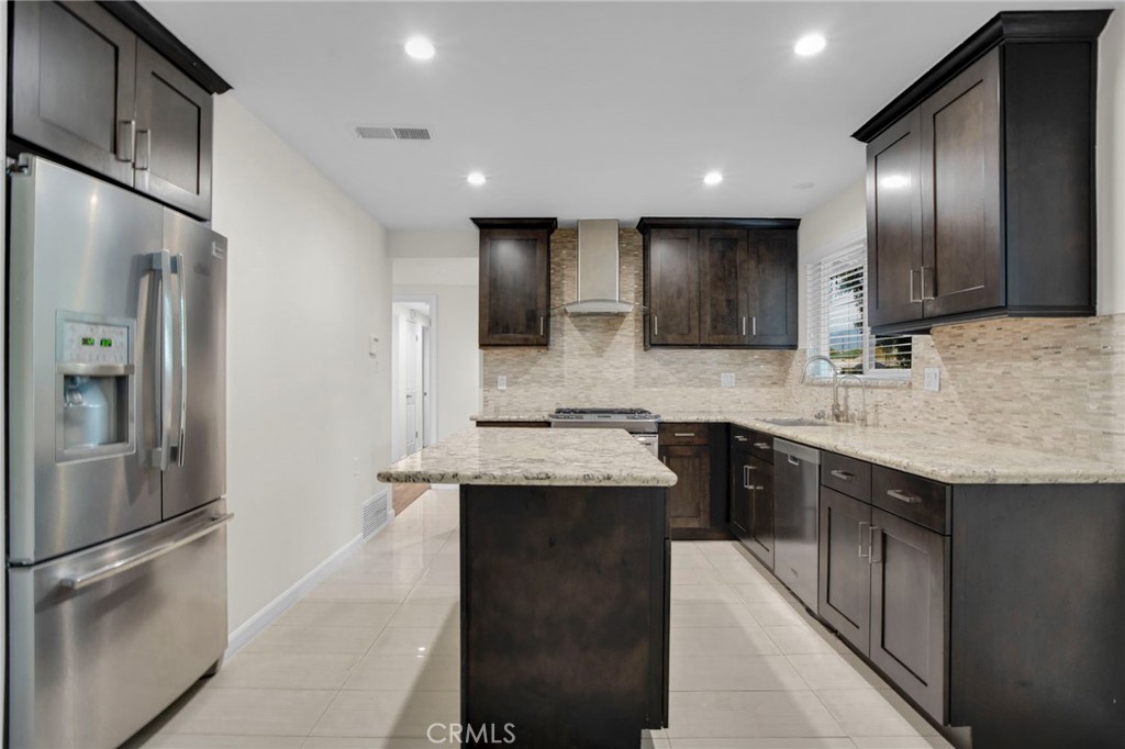 a kitchen with stainless steel appliances kitchen island granite countertop a sink stove and refrigerator