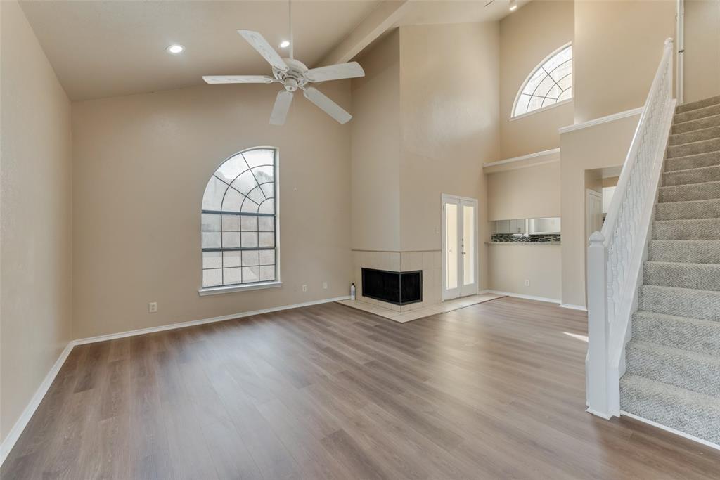 an empty room with wooden floor fireplace and windows