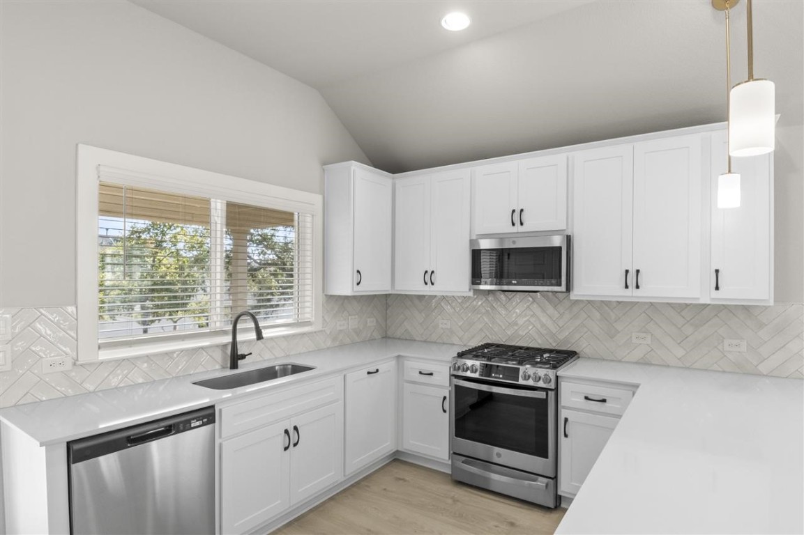 a kitchen with stainless steel appliances granite countertop a sink a stove and a microwave