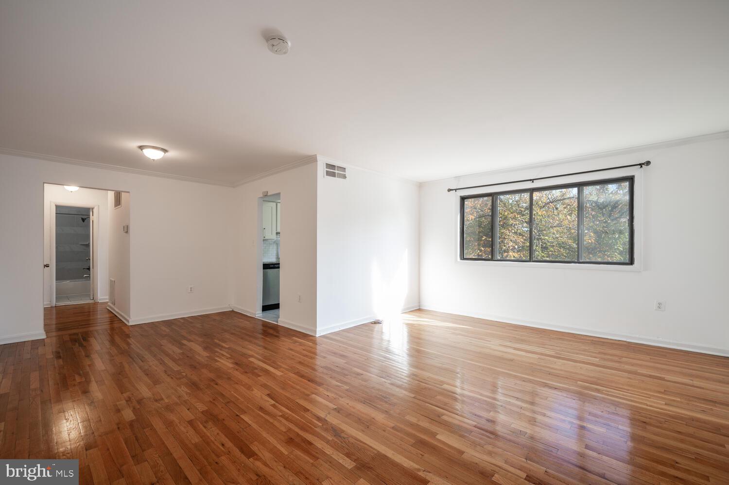 a view of an empty room with wooden floor and a window