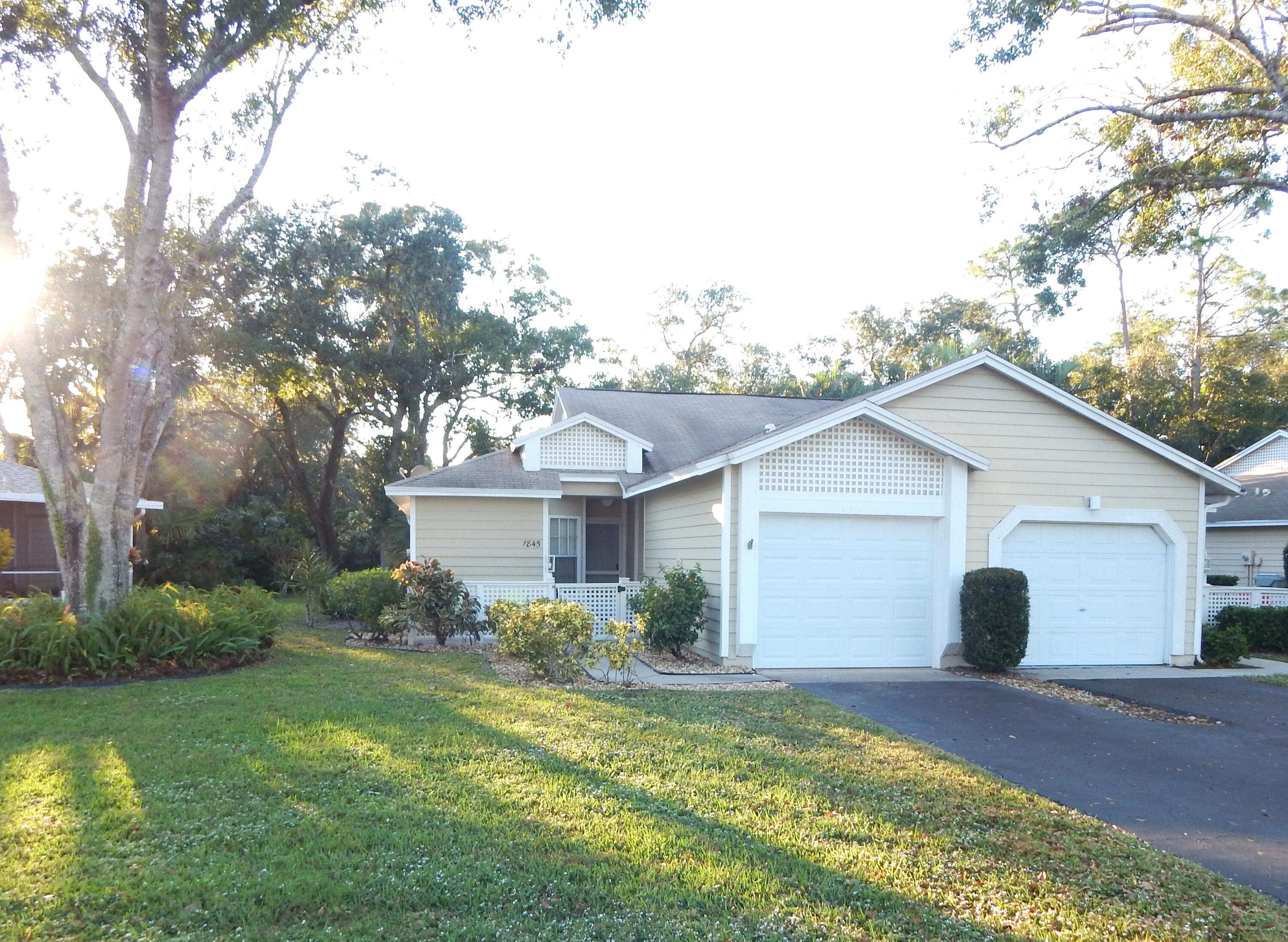 a view of a house with a yard and large trees