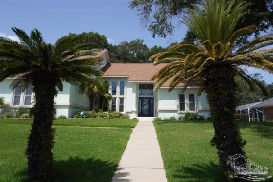 a front view of a house with a garden and trees