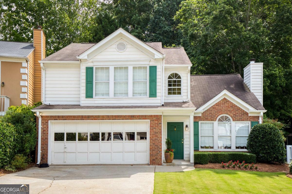 a front view of a house with a yard and trees