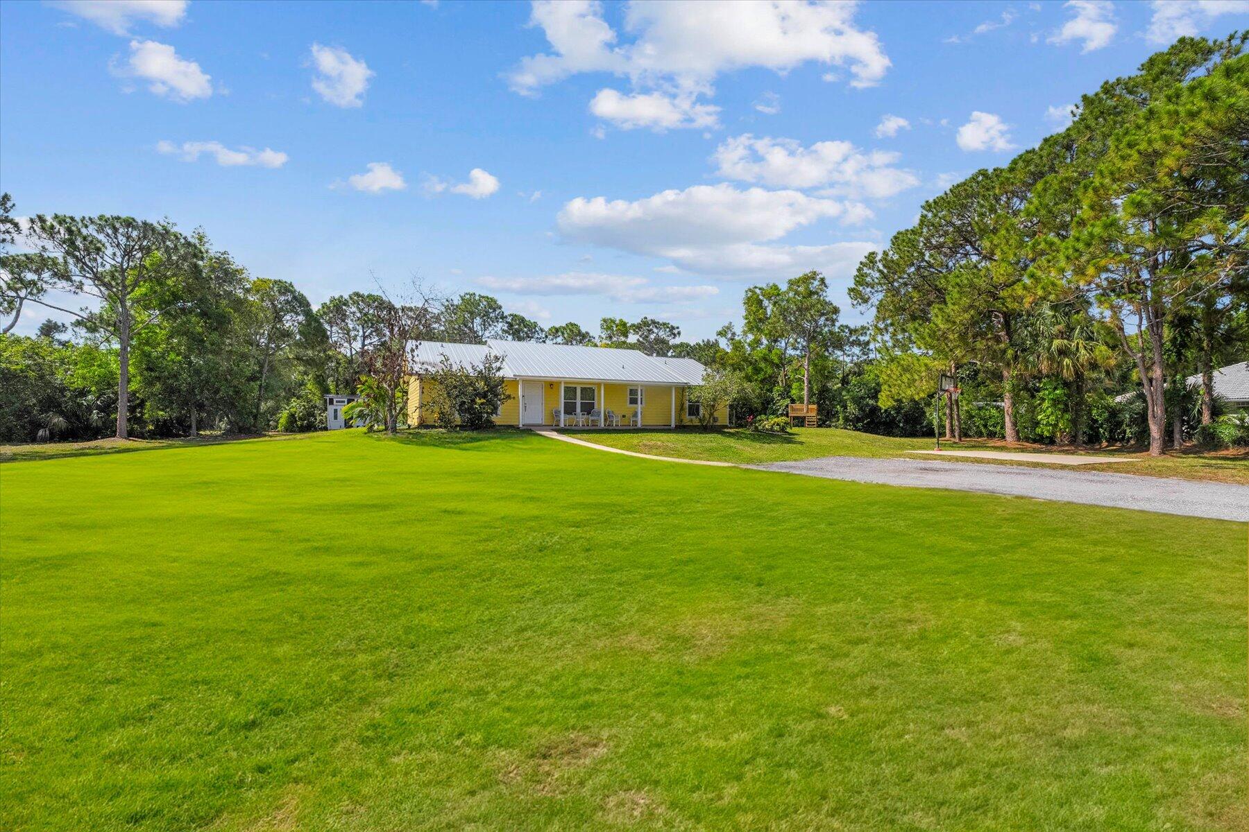 a view of building with huge green field and trees in the background