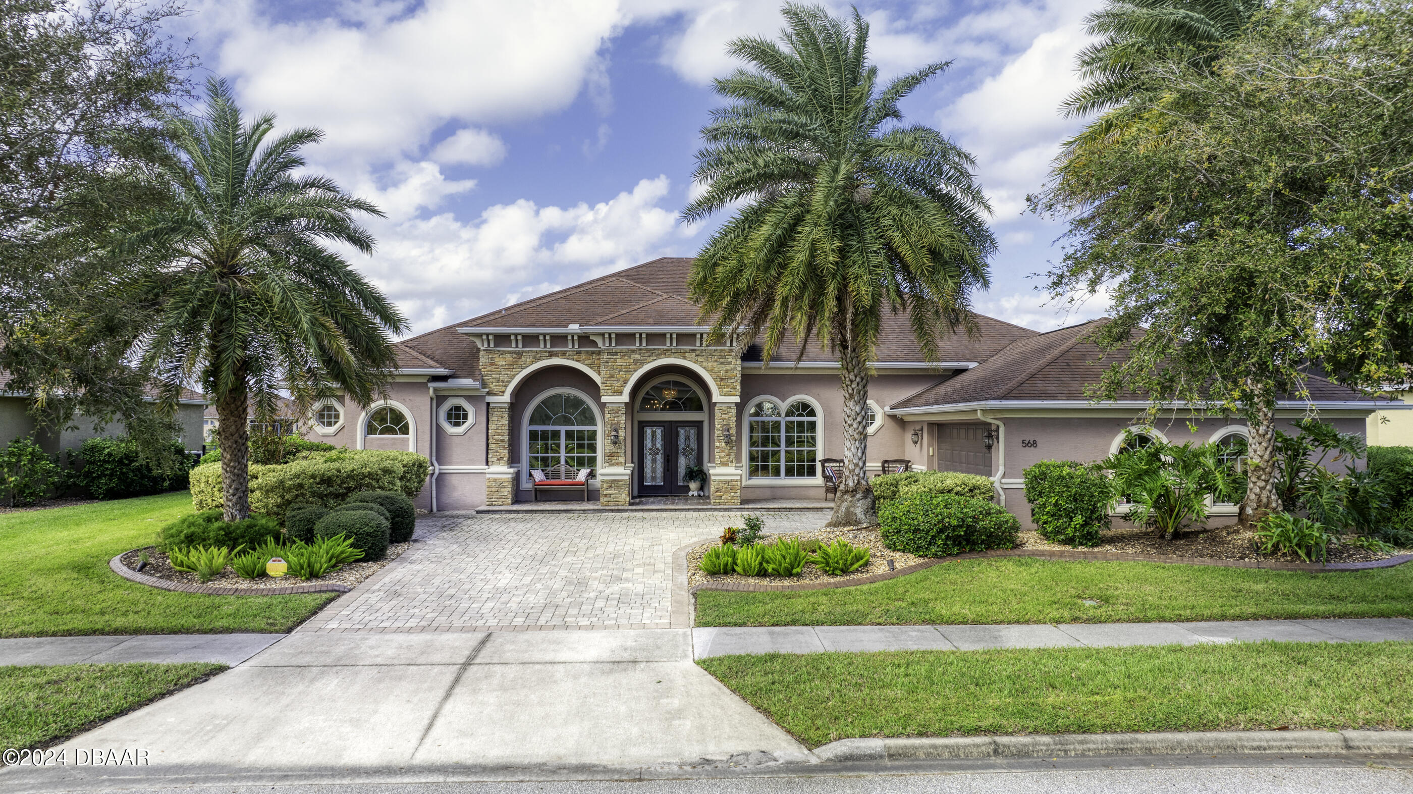 a front view of a house with a garden and trees