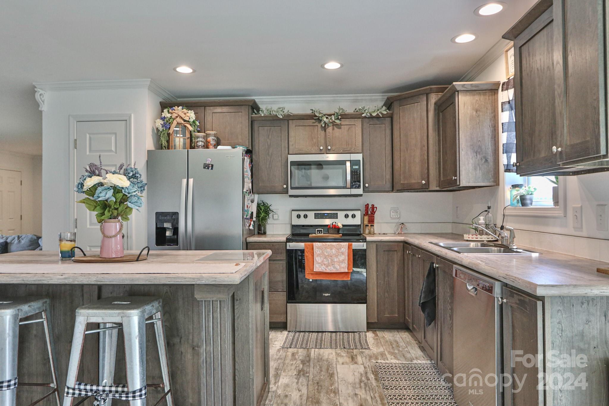 a kitchen with stainless steel appliances granite countertop a sink stove refrigerator and cabinets