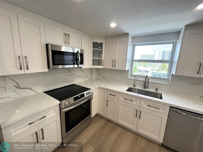 a kitchen with white cabinets appliances a sink and a window