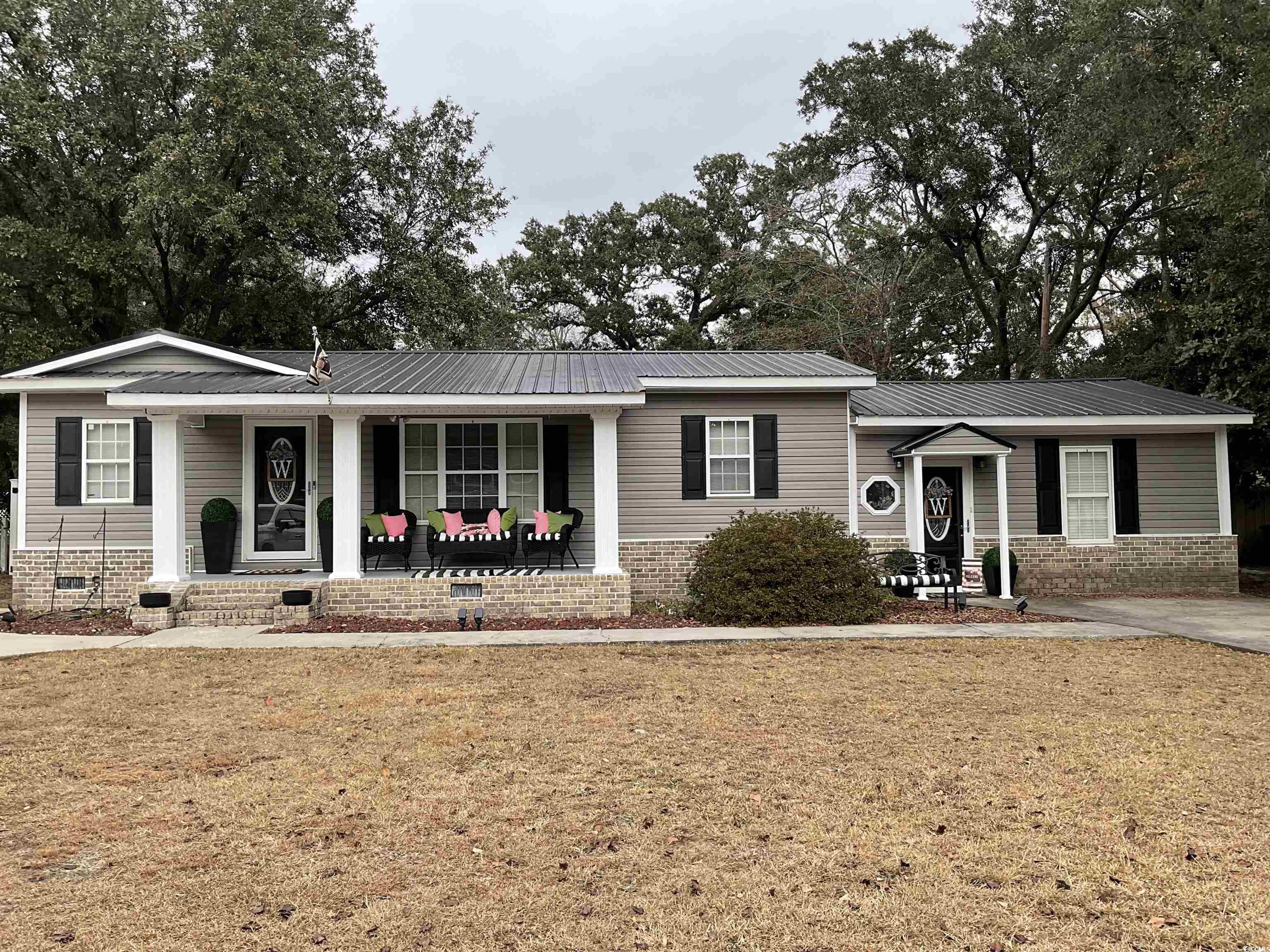 Ranch-style house with covered porch and a front y