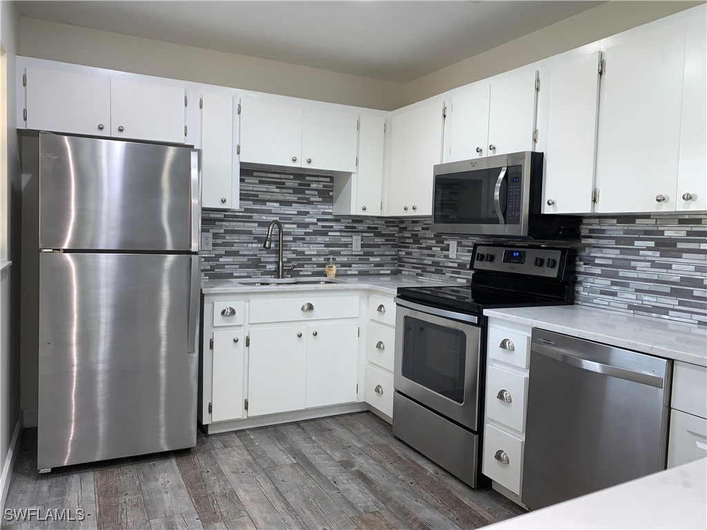 a kitchen with cabinets stainless steel appliances and wooden floor