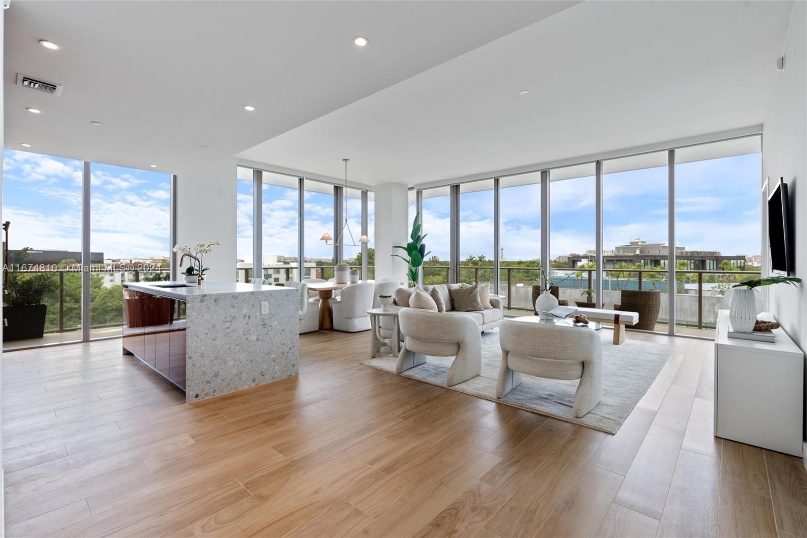 a living room with furniture large windows and wooden floor