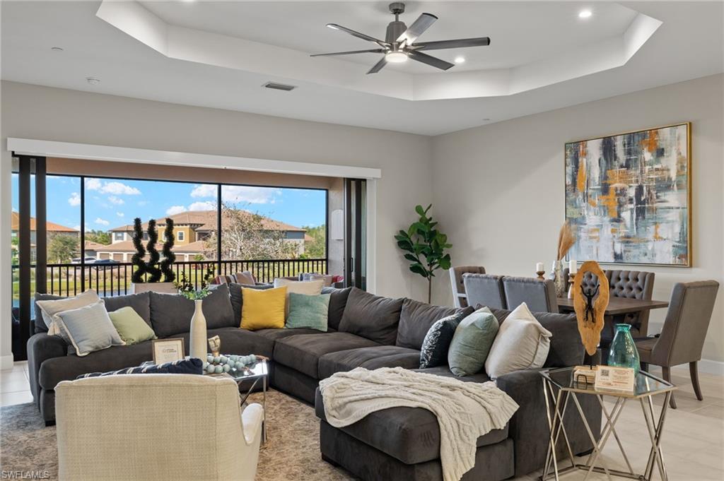 Tiled living room with ceiling fan and a tray ceiling.