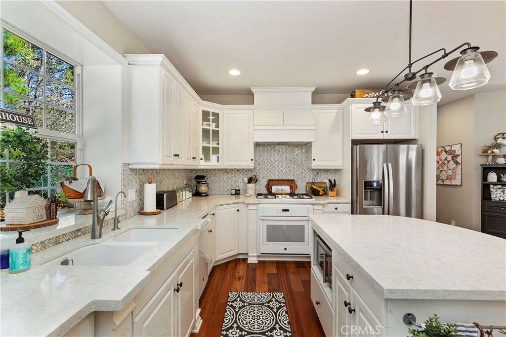 a kitchen with granite countertop a sink stainless steel appliances and white cabinets