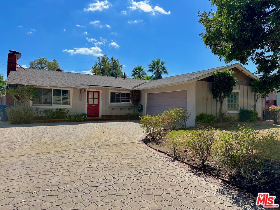 a front view of a house with a yard and potted plants