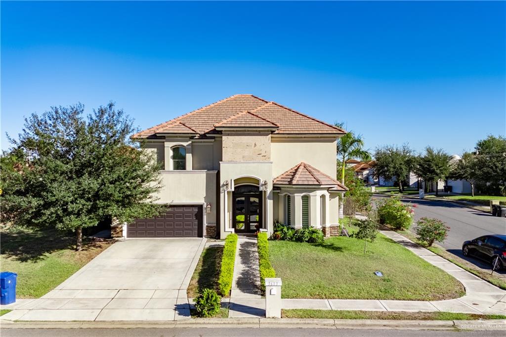 Mediterranean / spanish home with a garage, a front yard, and french doors