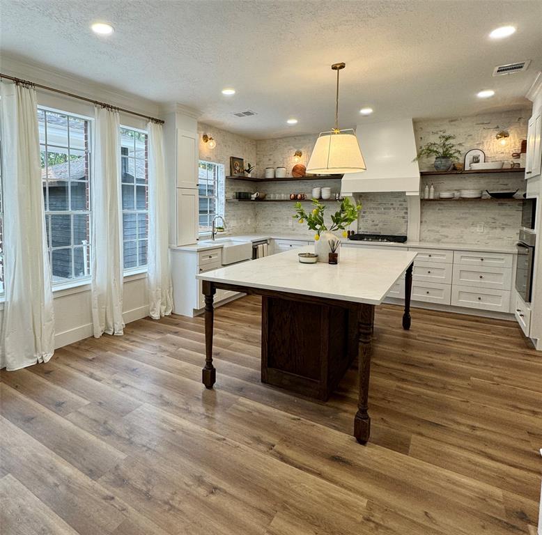 a kitchen with stainless steel appliances granite countertop a table chairs stove and wooden floor