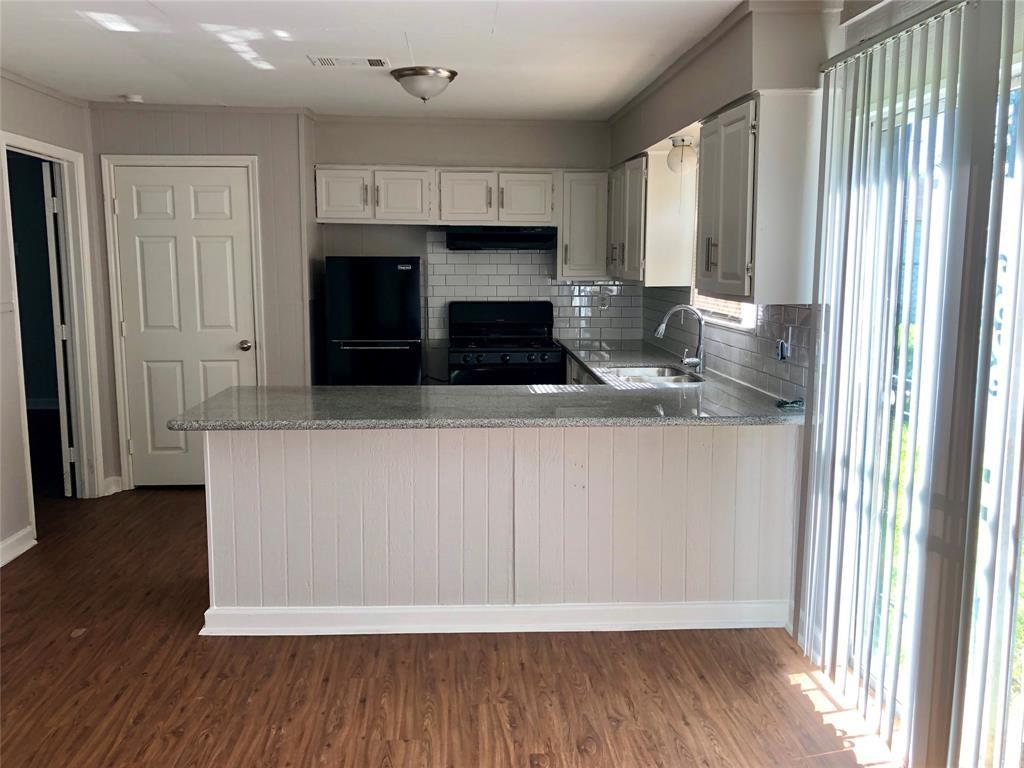 a kitchen with granite countertop a stove a sink and a refrigerator