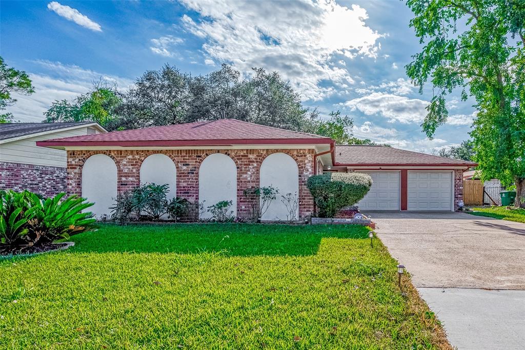 Charming single-story brick home with a neatly manicured lawn and mature trees. Features a two-car garage and a welcoming front facade with arched accents.