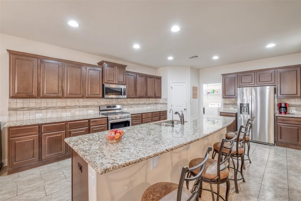 a kitchen with stainless steel appliances granite countertop a table chairs sink refrigerator and microwave