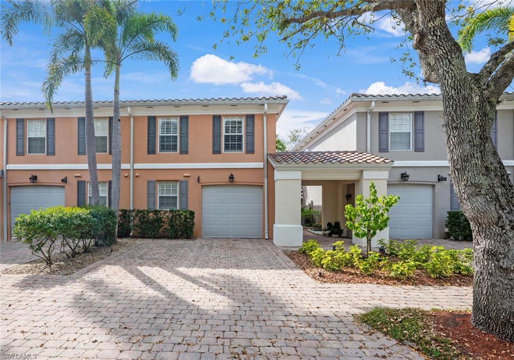 Townhome / multi-family property with a garage, a tiled roof, decorative driveway, and stucco siding