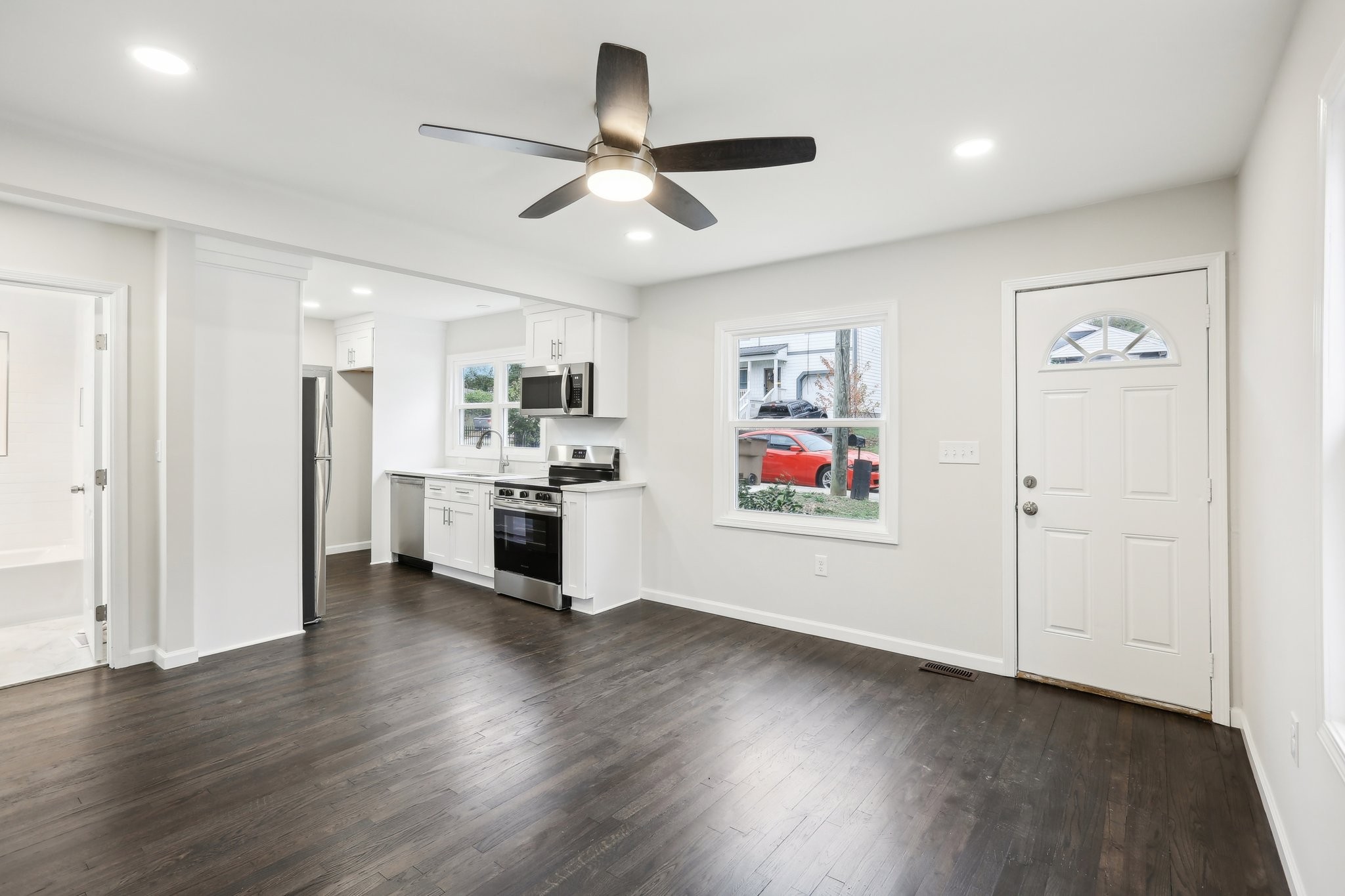 a view of a big room with wooden floor a ceiling fan and windows