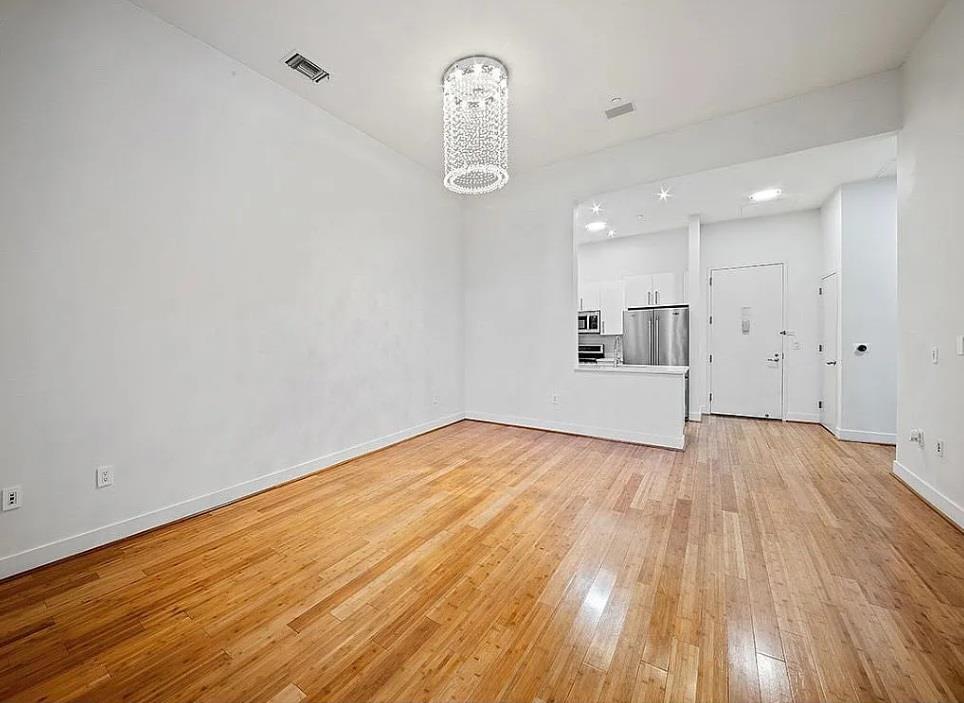 Unfurnished living room with light hardwood / wood-style flooring and a chandelier